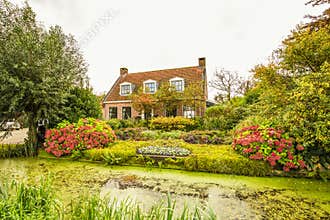 Rustic house with beautiful garden with borders with many flowering plants