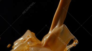 Closeup shot of cold coffee being poured on ice cubes with black background