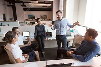 Millennial male leader working with diverse team at office.
