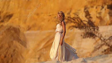 Beautiful bride is wearing fashion flying dress and wreath in the great desert in Dubai.
