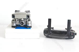 Drone and remote control next to some books in a drone pilot classroom against a white background. No people