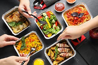 People eating from lunchboxes at grey table. Healthy food delivery
