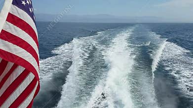 American flag and the water wake behind a speeding boat.