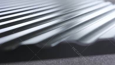 Close up side of black wavy roof tiles on blurred background. Action. Black wavy roofing material, constructional