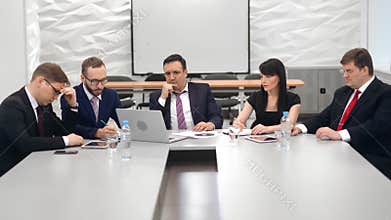 Confident male boss thinking looking on laptop at business meeting analysing problem
