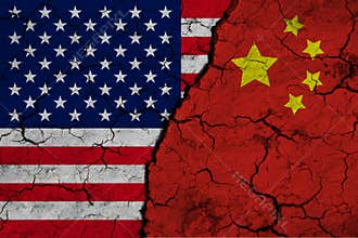 A closeup view of the US flag and the flag of China against the backdrop of cracked earth. The concept of the crisis of the war of