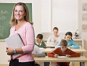 Teacher standing with notebook in classroom