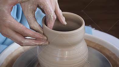 Girl Potter sculpts a pitcher of clay on a Potter`s wheel.