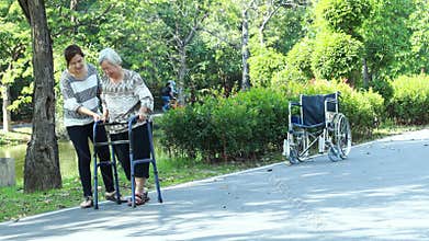 Asian senior woman use walking aid during rehabilitation after knee surgery, young carer assisting reassuring elderly people pract