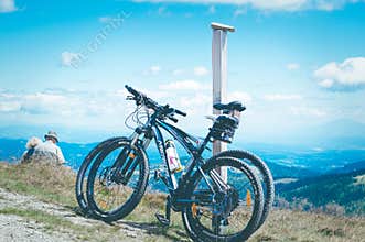Elderly people, man and woman, enjoy the view of the mountains, relax in the mountains after a bike ride.