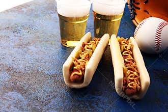 Grilled hot dogs with mustard and ketchup on the table with draft beer. Baseball party food with balls for the playoffs