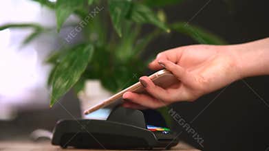 Contactless payment method. The girl applies the phone to the banking terminal.