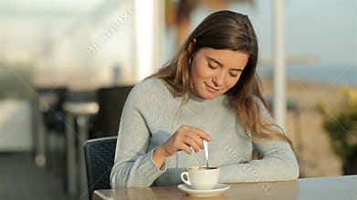 Girl stirring coffee sitting in a restaurant in slow motion