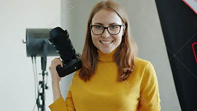 Portrait of successful female photographer beautiful woman holding camera in studio