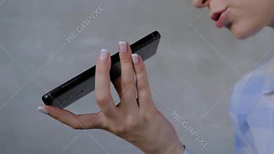 Woman holding smartphone and using voice recognition function - close up view
