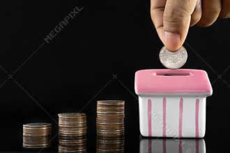 Savings concept for buying a house, Hand putting money coin stack with piggy bank