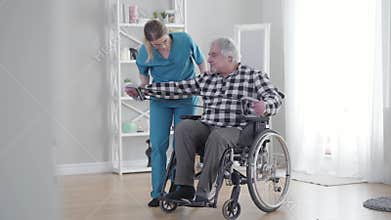 Long shot of concentrated Caucasian woman helping old man to stretch elastic band. Mature retiree exercising with the