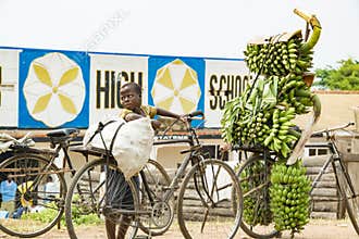 Boy with heavy load on his bike in Uganda. Boy carrying loads on bike. Bicycles loaded with plantains, cooking bananas and bags