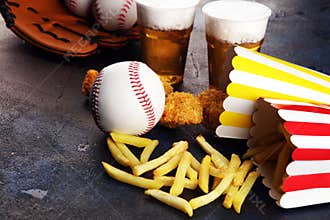 Chicken nuggets and french fries on the table with draft beer. Baseball party food with balls for the playoffs
