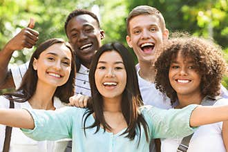 Group of multi-ethnic teen friends taking selfie picture outdoors