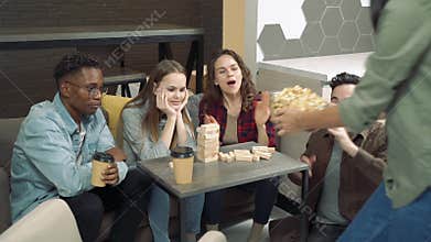 Group of multinational friends playing block removal game in the living room at home.