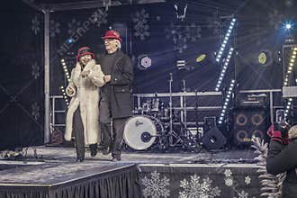 Elderly couple demonstrates hats at a fashion show.