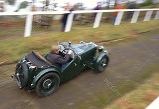 Senior man racing vintage car on hill climb track.