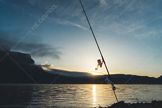 Fishery concept, outline fishing rod at sunrise sunlight, hobby sport on mist evening lake, catch fish on river on background