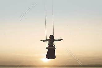 Special contact between nature and a woman with open arms on a swing
