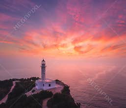 Lighthouse on the mountain peak at colorful sunset in summer
