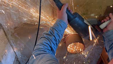 Young man works using angle grinder machine on steel pipe
