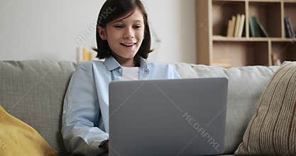 Boy Typing on Laptop and Expressing Amazement on Living Room Couch