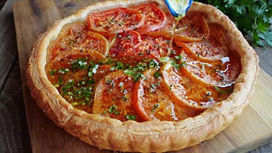 Puff pastry pie tart with tomato pour the sauce with olive oil, herbs and garlic. Close up.