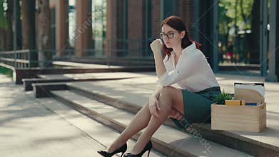 Ginger businesswoman feeling sad because her boss fired her. Woman in glasses is tortures herself sitting near the