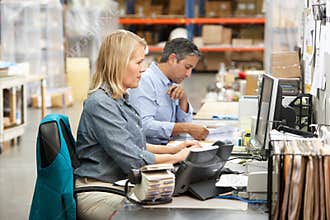 Business Colleagues Working At Desk In Warehouse