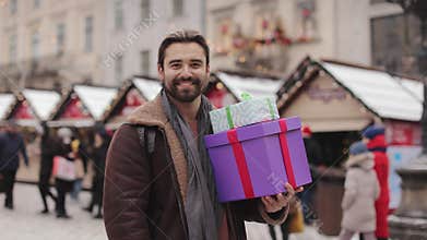 Man with gift boxes standing on street during winter holiday