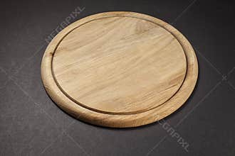 Round wooden breadboard on grey