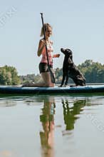 Dog owner and her black labrador retriever on a sup board