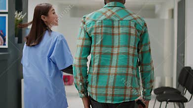 African american patient going in medical office with asian nurse
