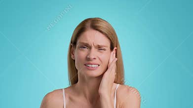 Acute dental pain. Unhappy middle aged woman suffering from acute toothache, touching her painful jaw, slow motion