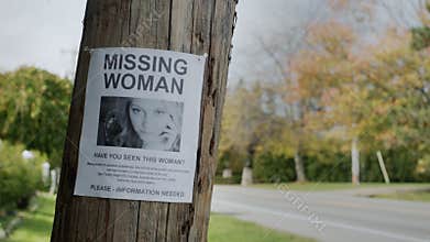 Poster for a missing young woman hangs on a pole near the road