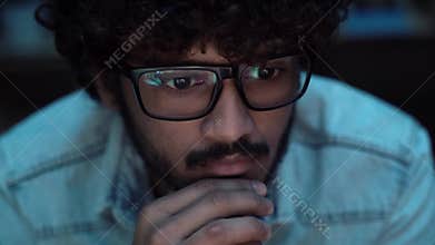Indian crypto trader analyst wearing eyeglasses working looking at computer.