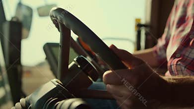 Driver hand controlling steering wheel on autumn agricultural field closeup.