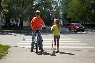 Boy with bicycle and his sister with scooter stand
