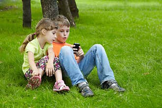 Boy and his sister sit and play electronic game