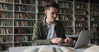 Student writes assignment in copybook seated in library
