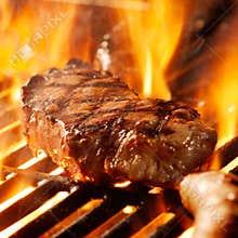 Beef steak on the grill with flames.