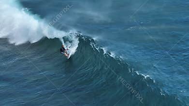 An athlete on a wave board rides the big ocean waves of a living reef in the Indian Ocean. One of the best surf spots on
