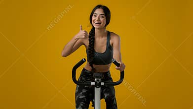 Indian ethnic smiling sporty woman female lady athletic girl cyclist biking flexing cycling riding on exercise bike