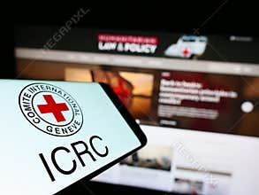 Cellphone with logo of International Committee of the Red Cross (ICRC) on screen in front of website.